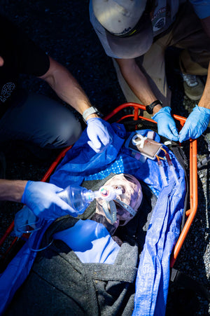 Remote EMT & Medical Care Person In Charge Students practice Bag Valve Mask ventilations and starting an IV during a night time medical scenario.