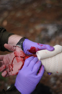A Wilderness First Responder Recertification (WFC) student practicing bleeding control and wound management.