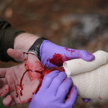 Load image into Gallery viewer, A Wilderness First Responder Recertification (WFC) student practicing bleeding control and wound management.