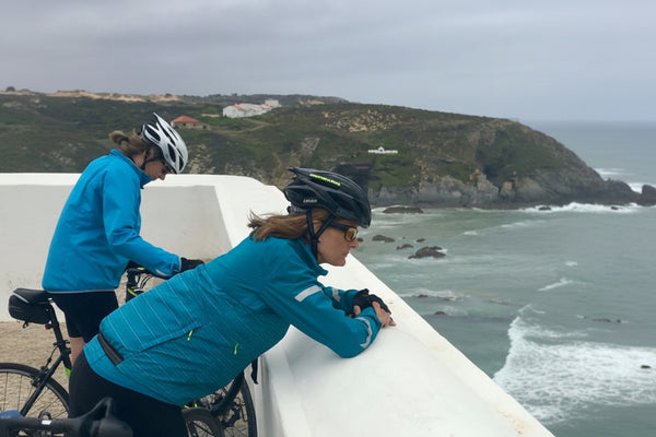 Two cyclists on a boat with a scenic coastal background