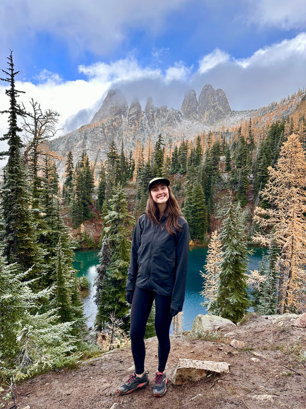 Sahale DelCampo standing in a mountainous landscape with a lake and trees.