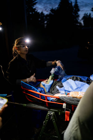 wilderness First Responder and Wilderness EMT/Remote EMT students manage a unconscious and apneic patient in a litter while participating in a Remote Medical Training night scenario that simulates a real life emergency in a austere environment. 