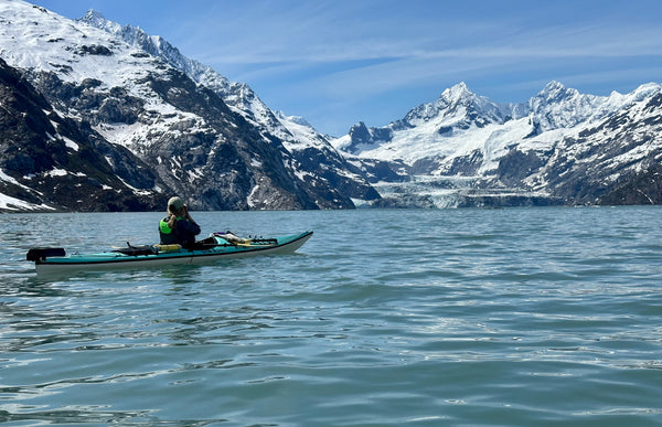 Libby Feldhaus kayaking on a lake with snow-capped mountains in the background