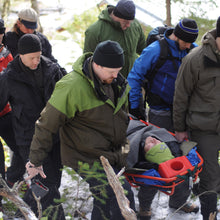 Load image into Gallery viewer, Wilderness First Responder Recertification students practice packaging and transporting patients in litters. 